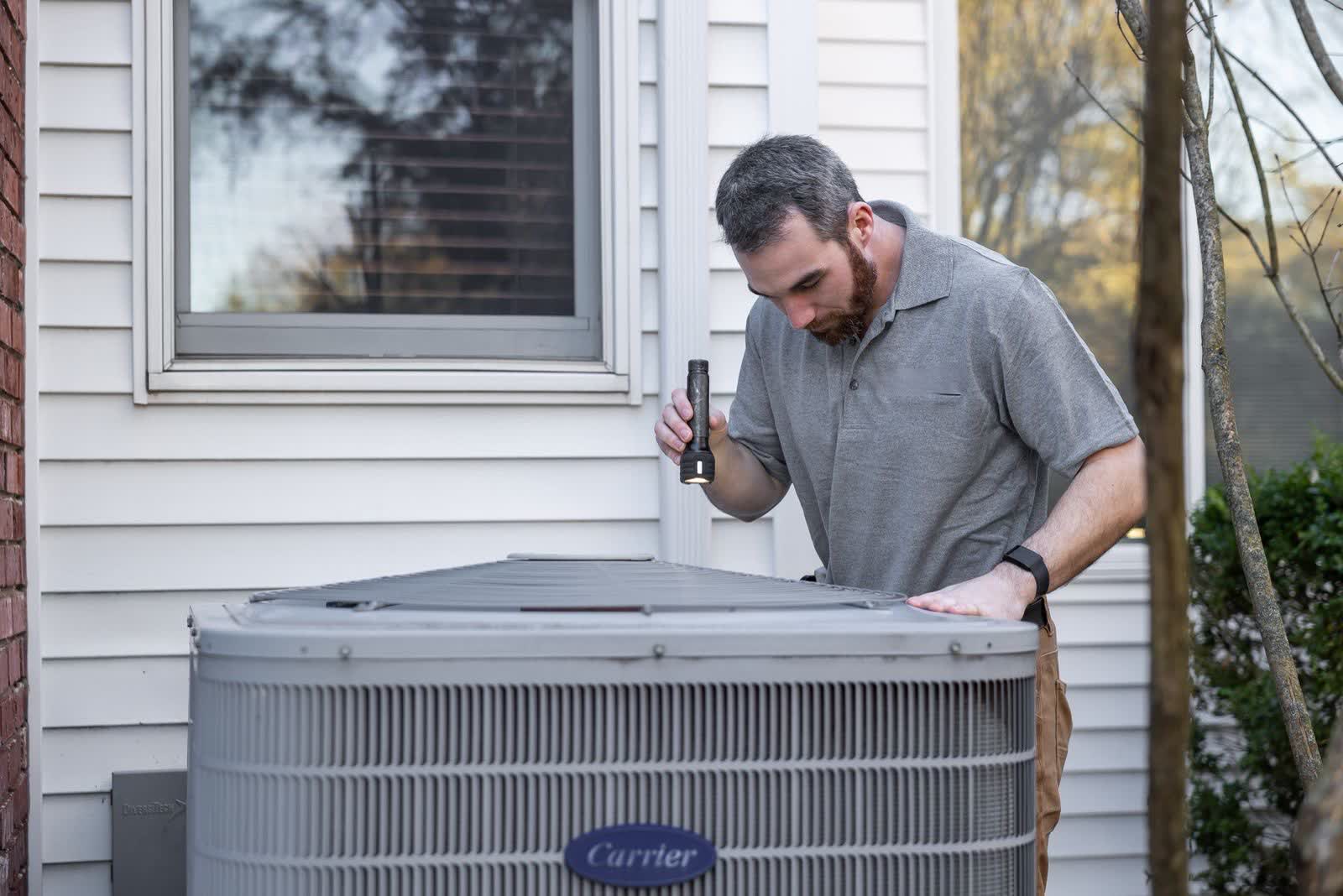 Technician inspecting an outdoor AC condenser unit