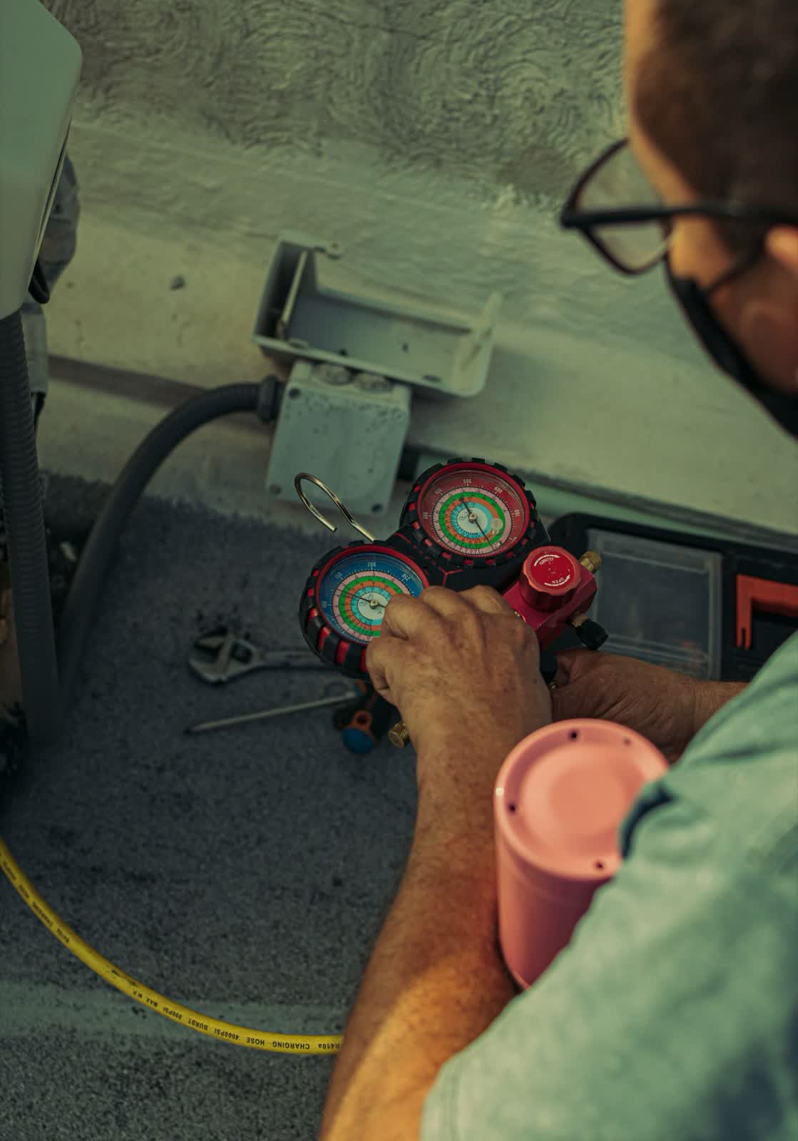 Technician reading refrigerant manifold gauges